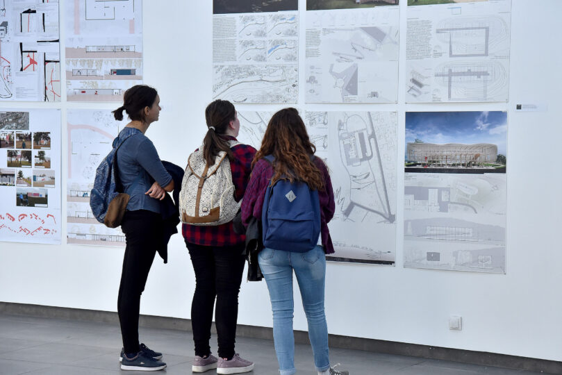 Three young people looking at information posters on a wall