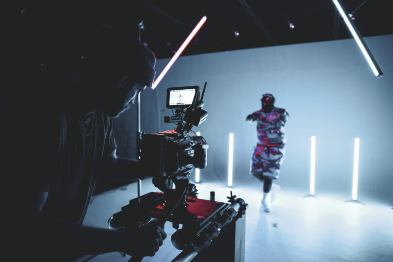 Videographer using a camera, facing a model