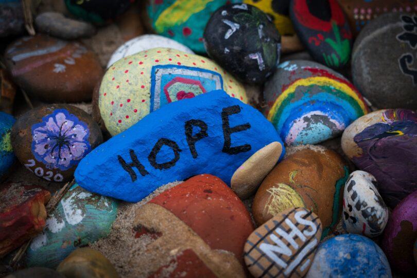 Painted pebbles, one reads 'Hope' one reads 'NHS', others have flowers and rainbows