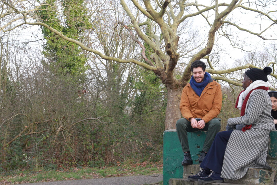 Two people sat talking beside a tree