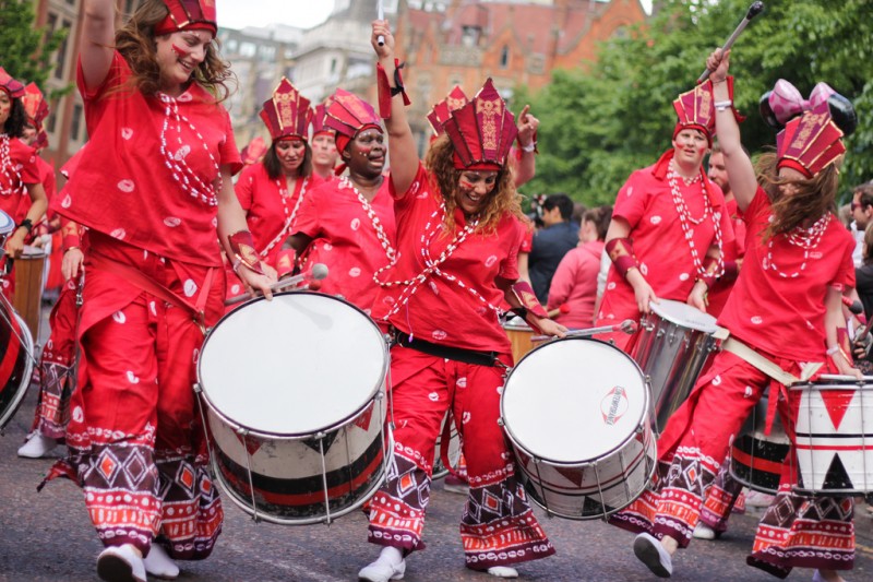 A parade of musicians with drums and red costumes