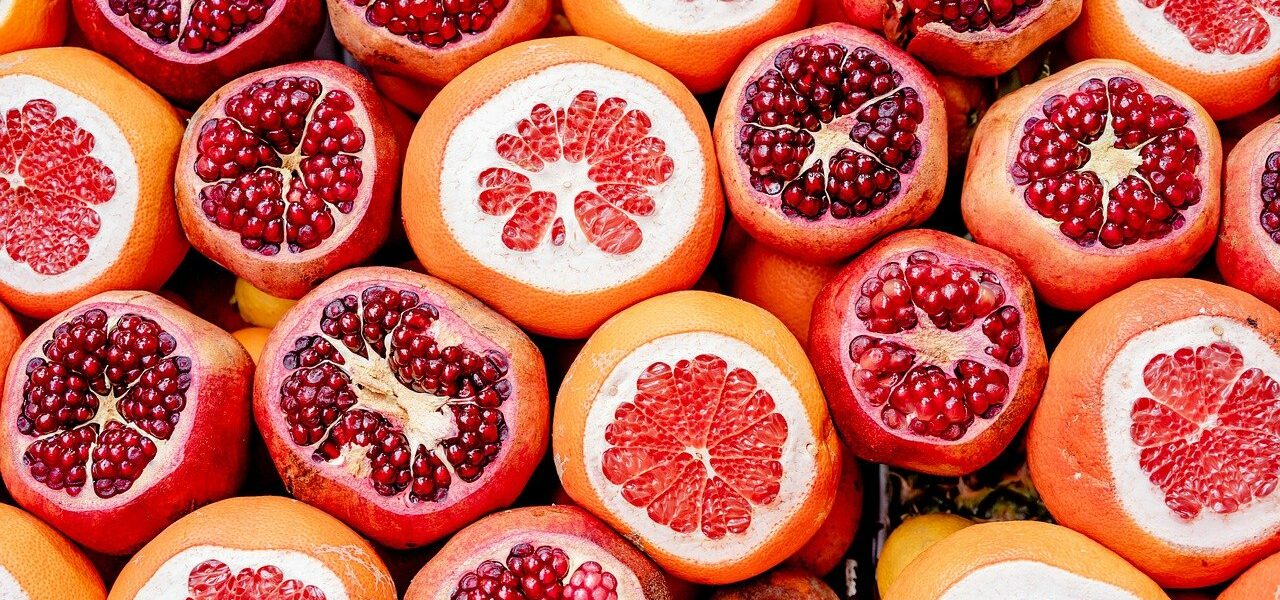 Several pomegranates that have had the tops sliced off, showing the seeds inside