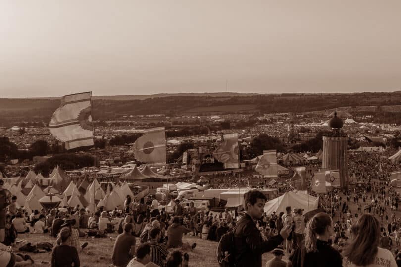 Photo of a festival site on a hill with flags and lots of people scattered around