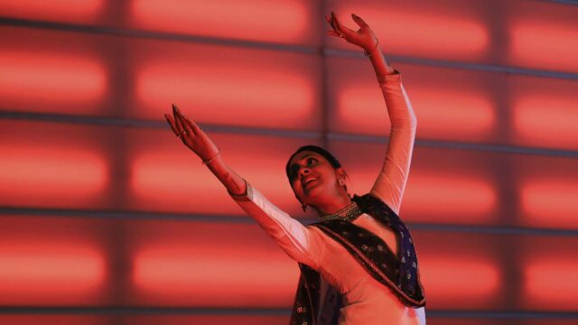 Balbir Singh dance company. Person mid dance move, arms raised