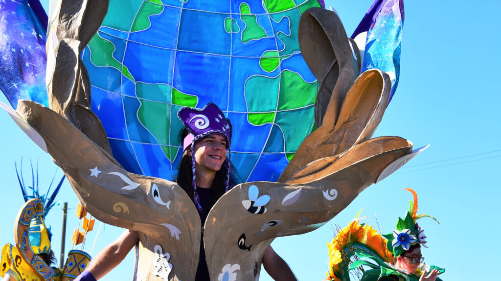 A person wearing an outfit with the Earth in a pair of hands at a carnival