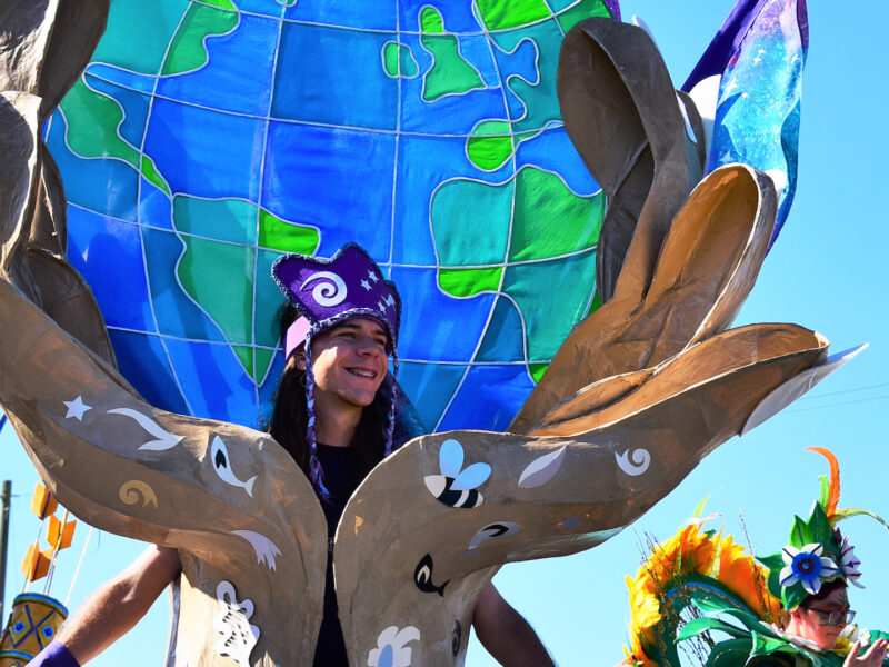 A person wearing an outfit with the Earth in a pair of hands at a carnival