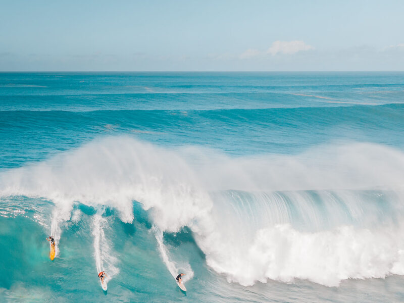 Image of sea with big waves and three surfers