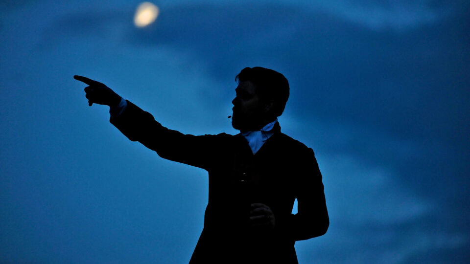 a silhouette of a person pointing against a night sky