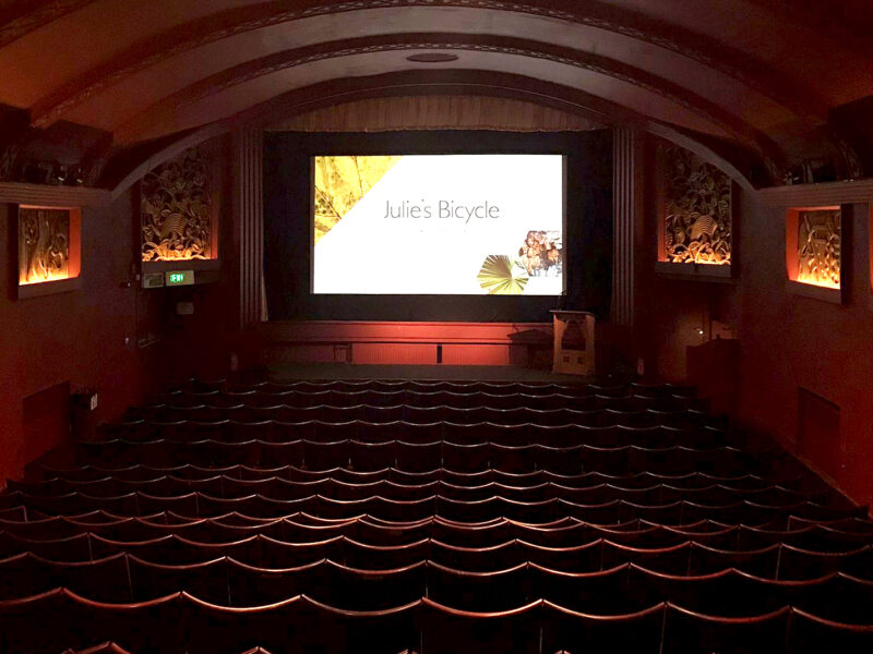 A cinema room filled with chairs. Julie's Bicycle logo is on the screen at the front.