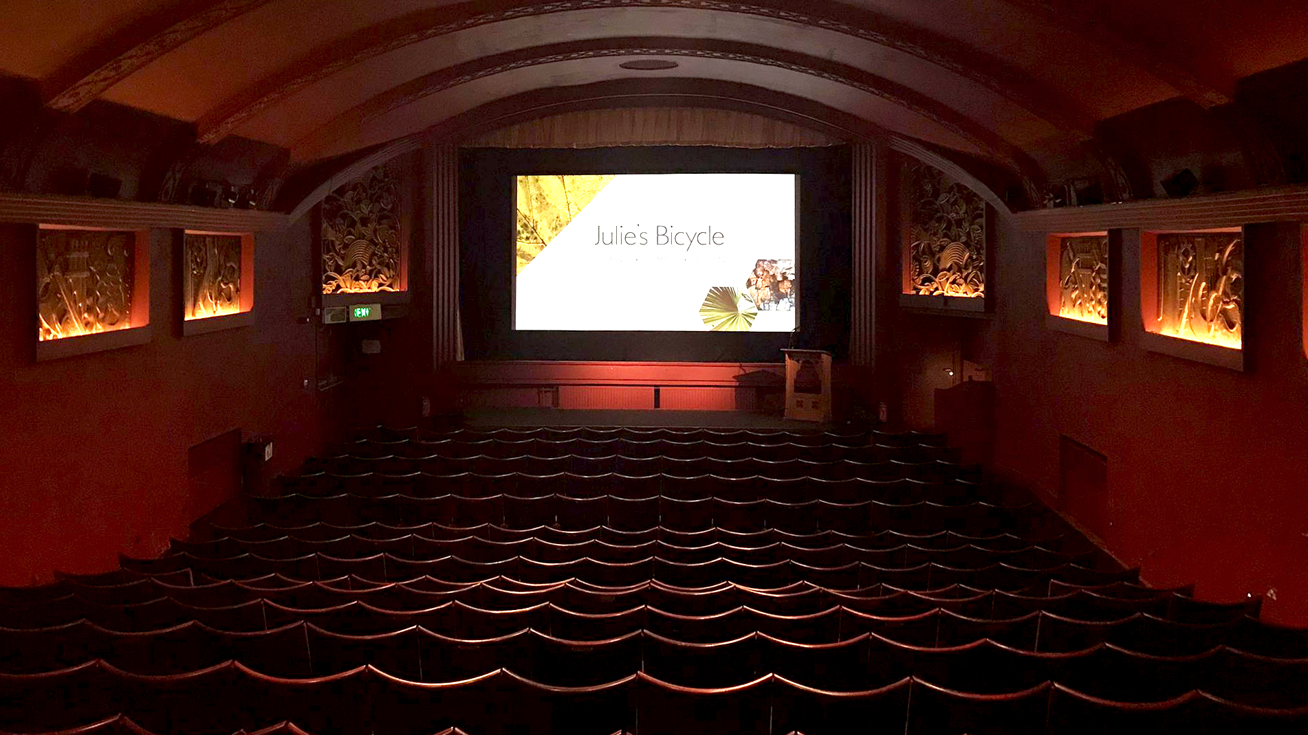 A cinema room filled with chairs. Julie's Bicycle logo is on the screen at the front.