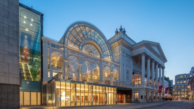 Glass fronted building at night with lights on inside