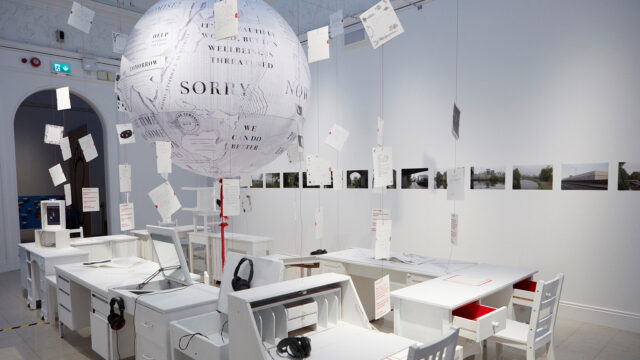 Model globe hanging over and empty classroom with the word 'Sorry' on it