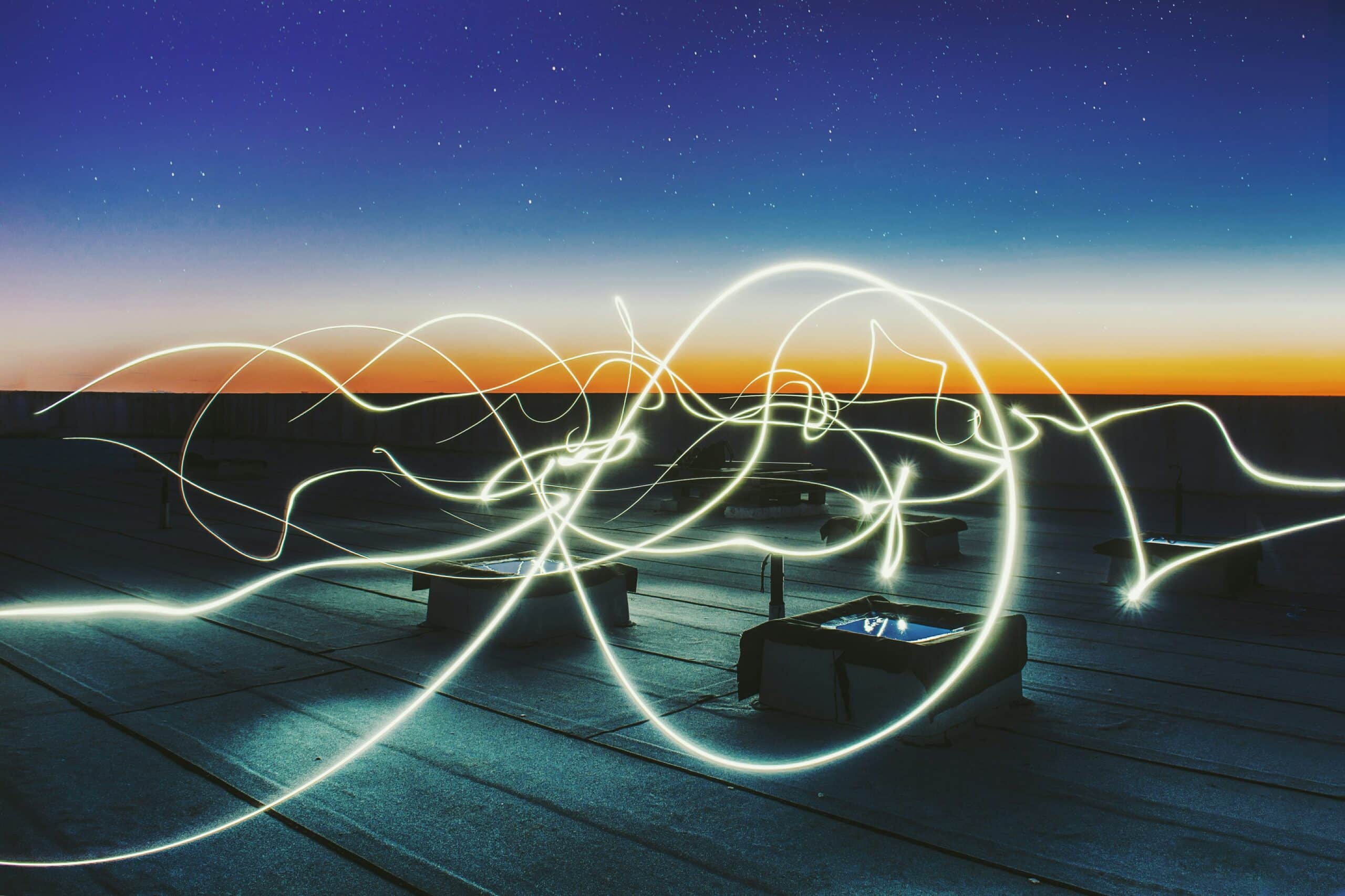 light trails in a night sky on a building roof