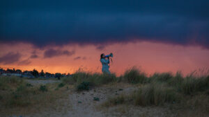 Person with megaphone during dawn or dusk on sandy dunes