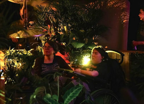 two people sat surrounded by lots of green plants indoors