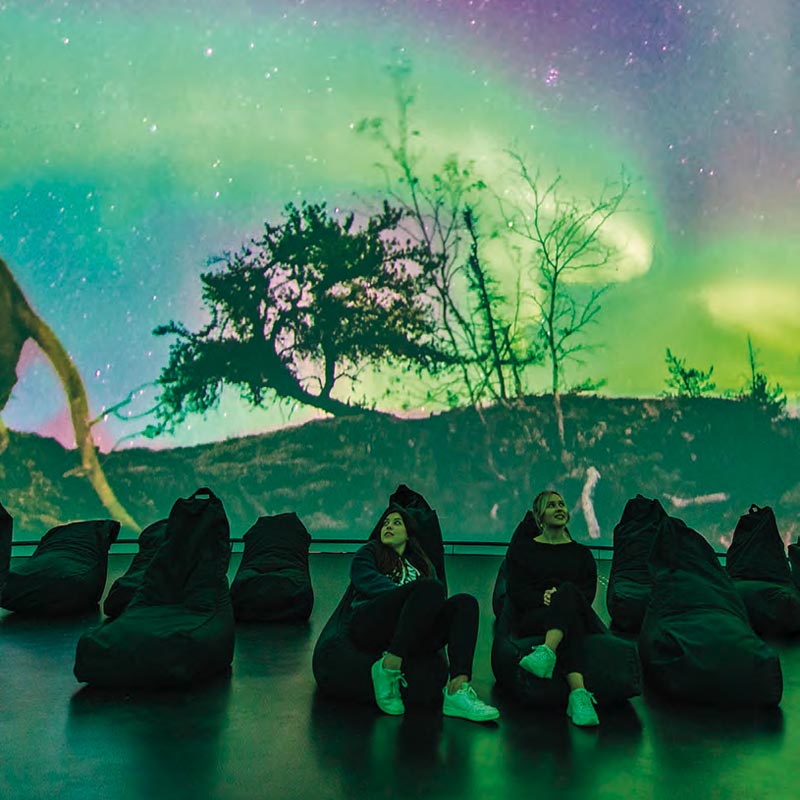 On stage with people sat on beanbags, with an image of the northern lights as a backdrop