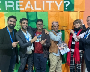 People stand in front of an orange and green colourful background with 'Reality?' written in white letters