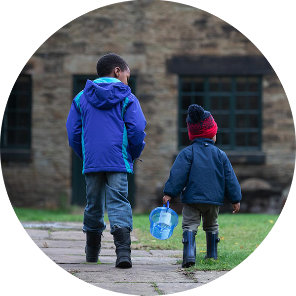 Two children from behind, walking outdoors with winter jackets on.