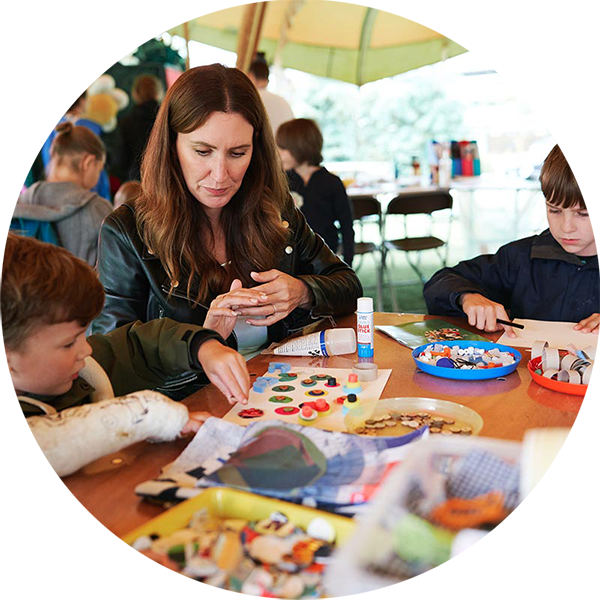 Two kids and an adult around a table, working on arts and crafts.