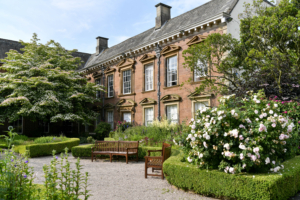 Outdoor image of Tullie House building with trees and blue sky, sunny day