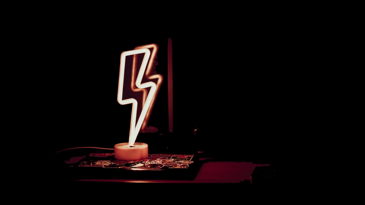 Glowing neon lamp in shape of lightning in dark room