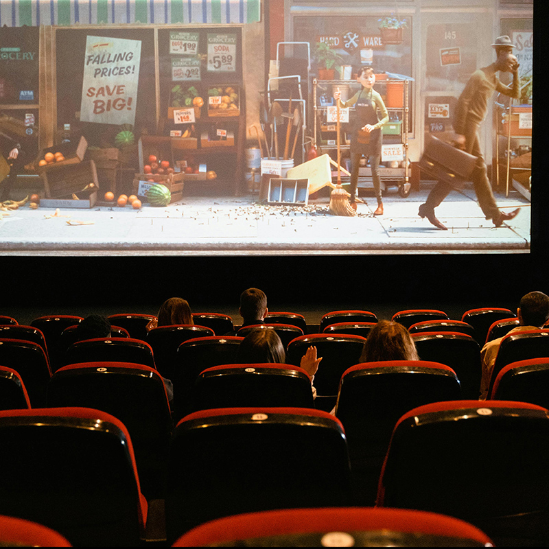 indoors at a cinema, screen is showing an animation