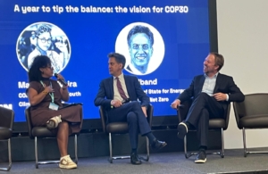 A women and two men sit on a stage giving a panel talk